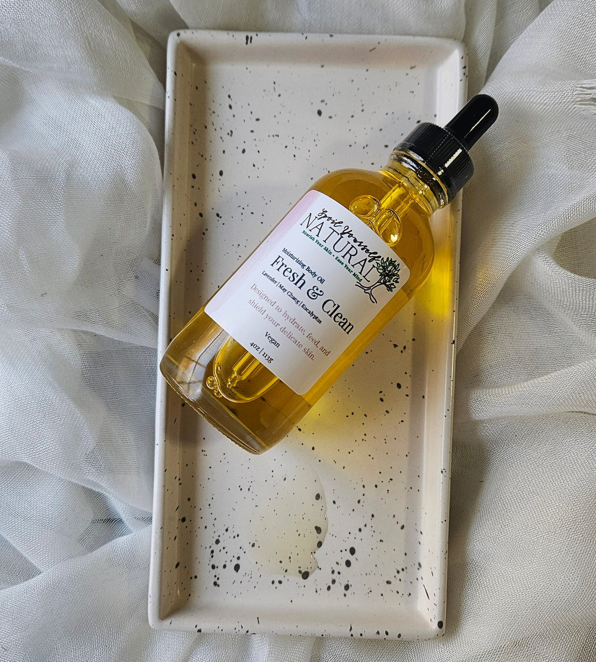 Bottle of 'Natura' fresh & clean product on a speckled tray with white fabric background