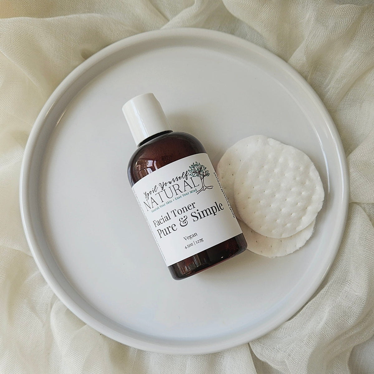 A bottle of gentle facial toner and a cotton pad placed on a white plate, with the product label visible.