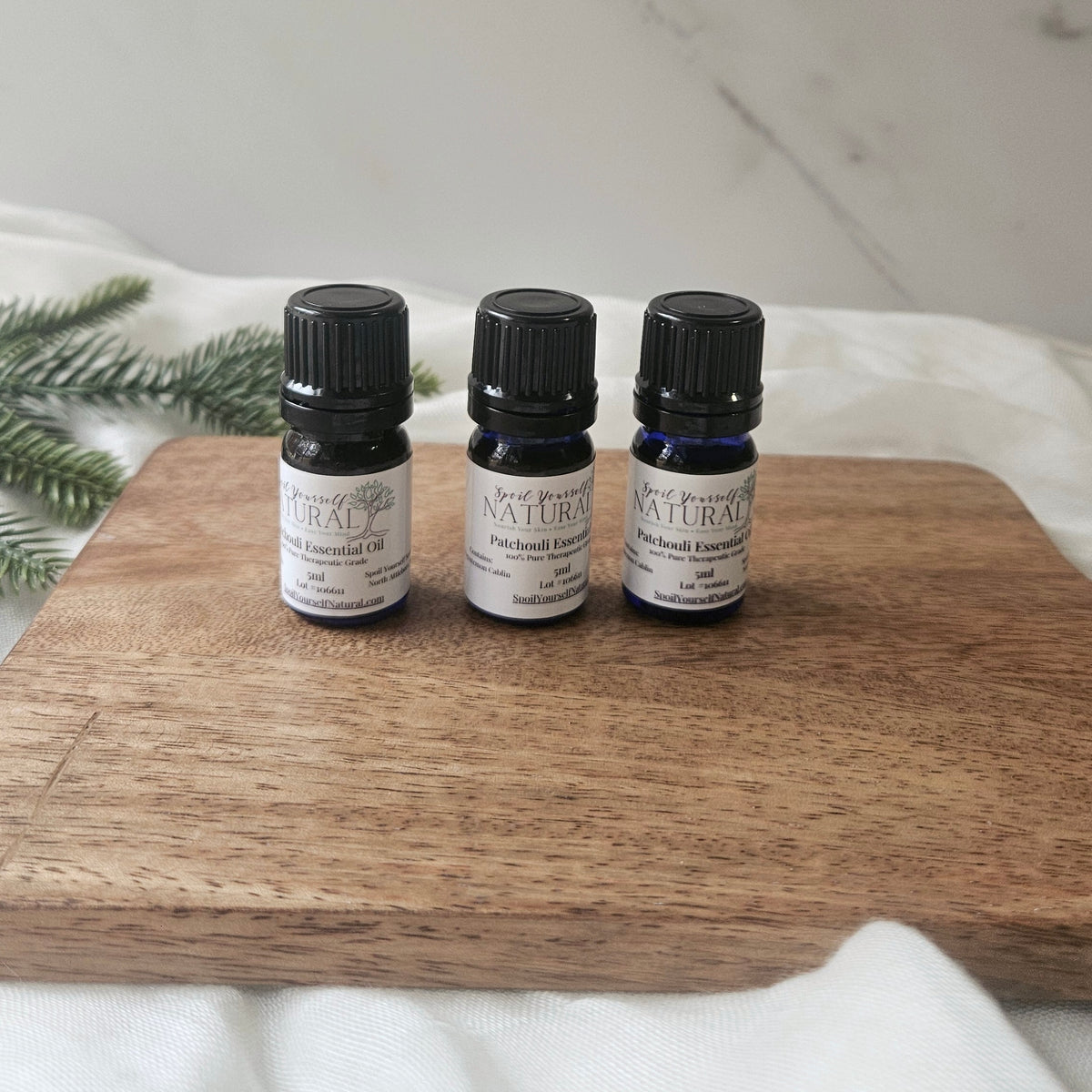 Three small essential oil bottles on a wooden surface with a white background