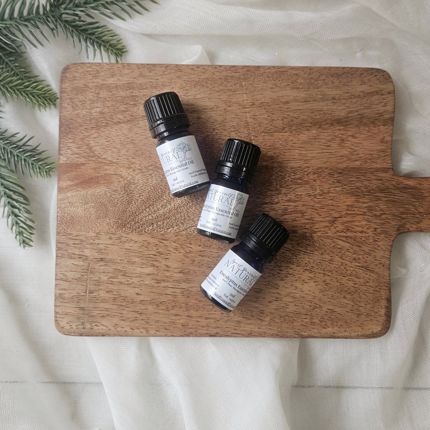 Three small bottles of Kiehl's on a wooden cutting board with a white background