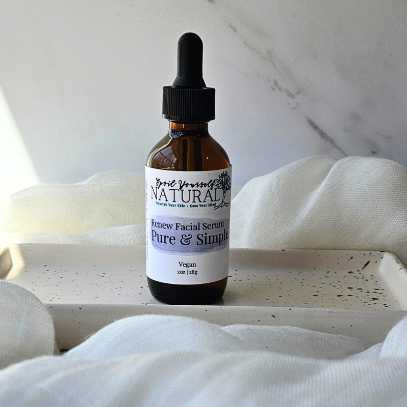 A bottle of Renew Facial Serum by April Beauty, with a dropper, positioned on a white surface with a marble background. The label on the bottle reads 'Renew Facial Serum, Pure & Simple, 2 oz'.
