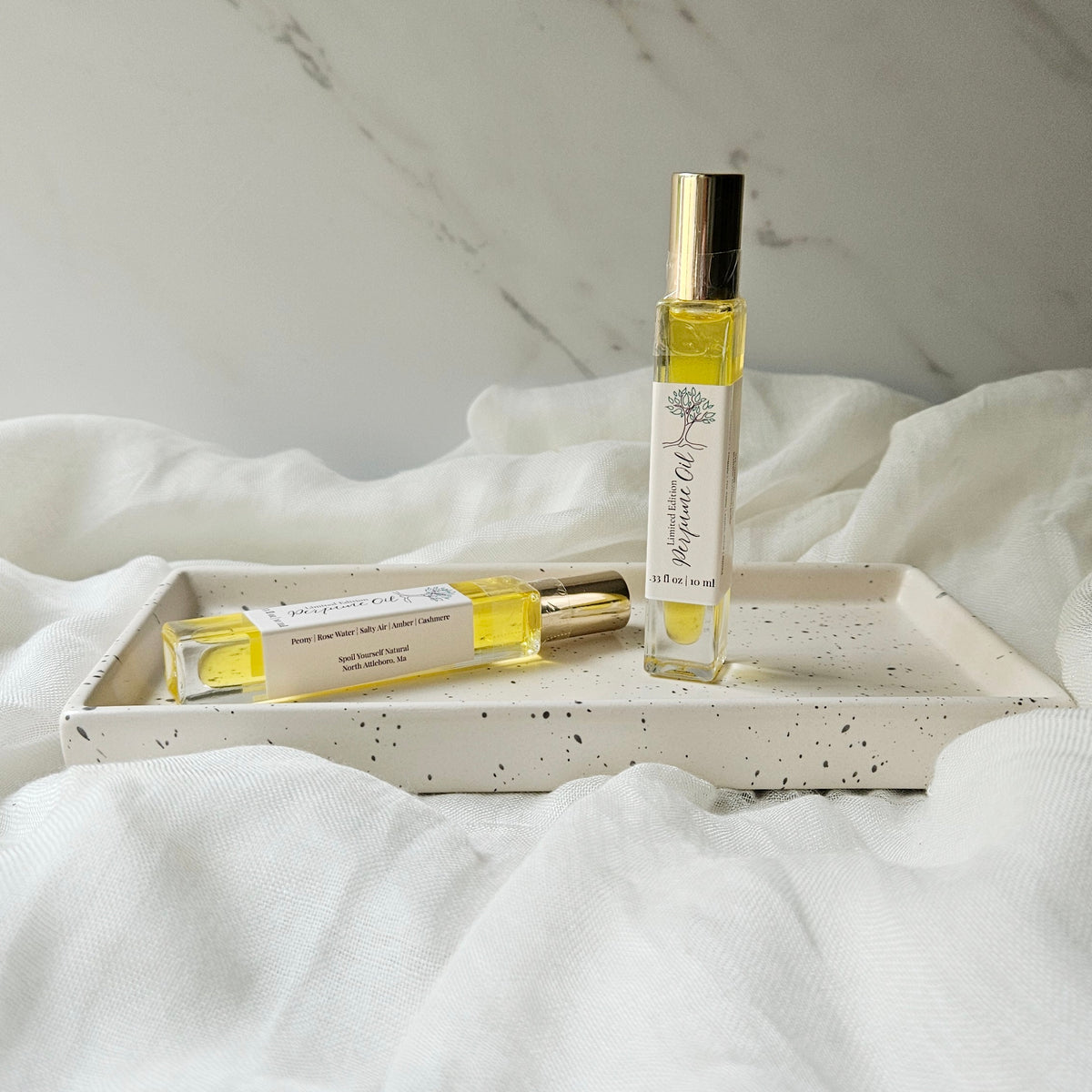 Two small bottles of perfume on a textured white surface
