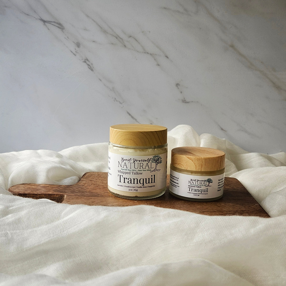 two different sizes of tallow placed on a wooden board with a marble background