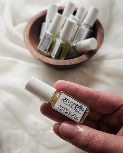 A small bottle of cuticle nail oil being held by a person with more bottles visible in the background.