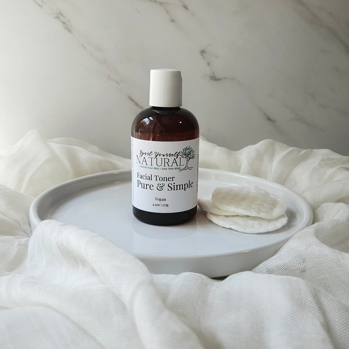 A bottle of gentle facial toner and a cotton pad placed on a white plate, with the product label visible.