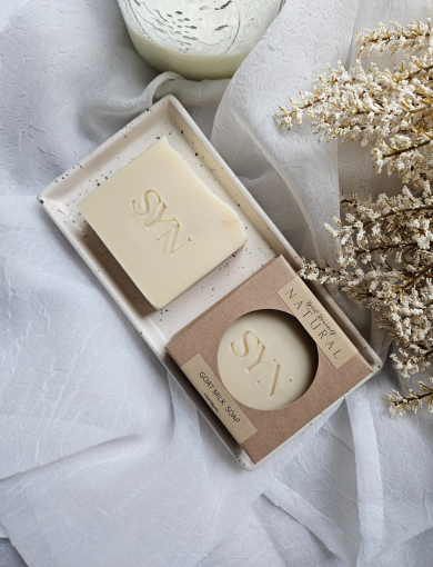 Two bars of soap, one larger and one smaller, with the brand 'S A' marked on them. The smaller bar is inside a cardboard sleeve with the same brand mark.