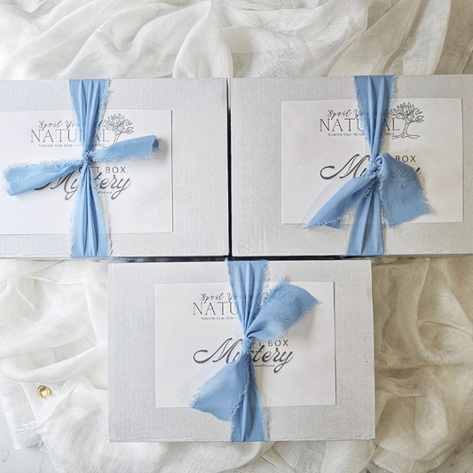 Three boxes with blue ribbons on a textured white surface