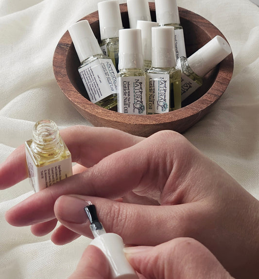 A small bottle of cuticle nail oil being held by a person with more bottles visible in the background.
