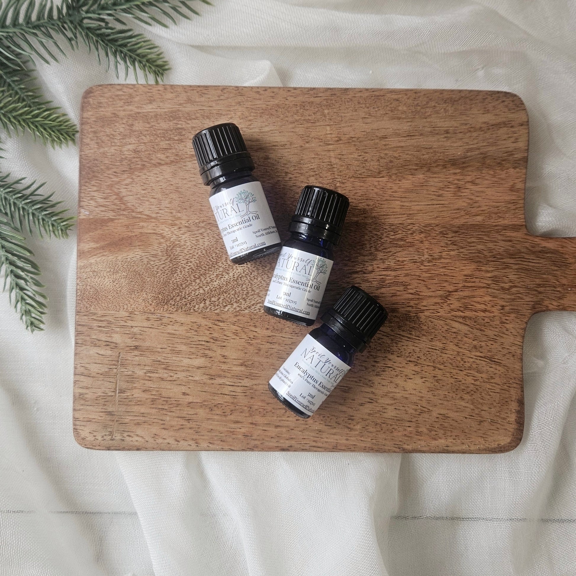 Three small bottles of Kiehl's on a wooden cutting board with a white background