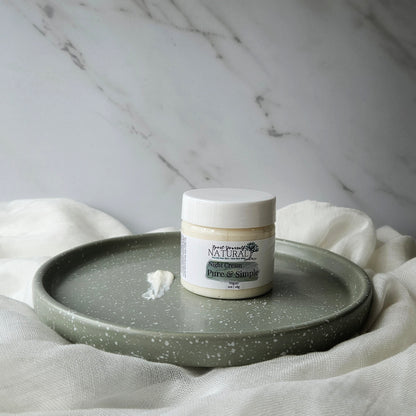 A jar of facial night cream placed on a ceramic plate with a small amount of cream spread out in front of it, all set against a marble background with a neutral color scheme.