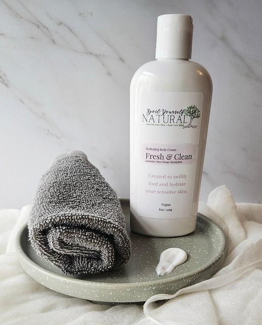 bottle of cream with a sample next to it to see thick texture on a speckled plate with a facial towel next to it