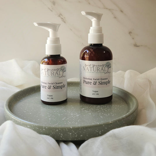 Two bottles of 'Pure & Simple' facial cleanser on a gray tray with a marble background.