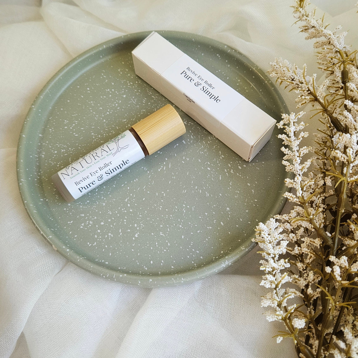 Skincare product and packaging on a green plate with a neutral background
