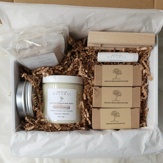 A gift bundle for sensitive skin containing packaged soaps, a jar of body butter, and a soap dish, all displayed in an open gift box.