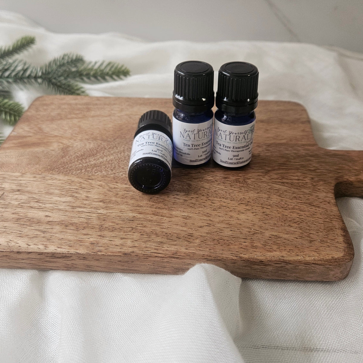 Three essential oil bottles on a wooden cutting board with a white background