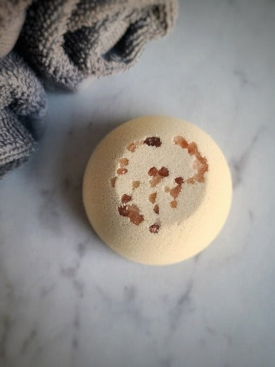 a single bath bomb on a granite surface with facial towels in the background