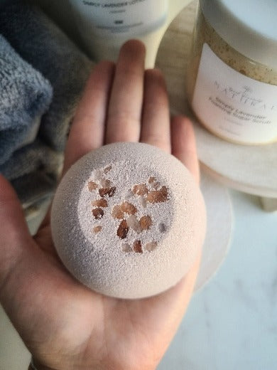 a picture of the lavender bath bomb placed in someones hand to show size