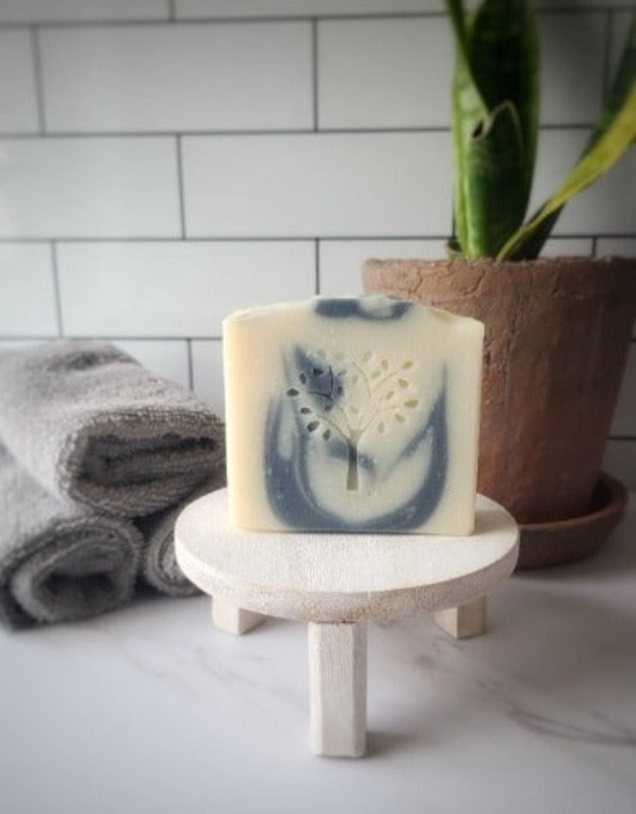 rainforest soap on a wooden stand with florals and wash clothes in the background